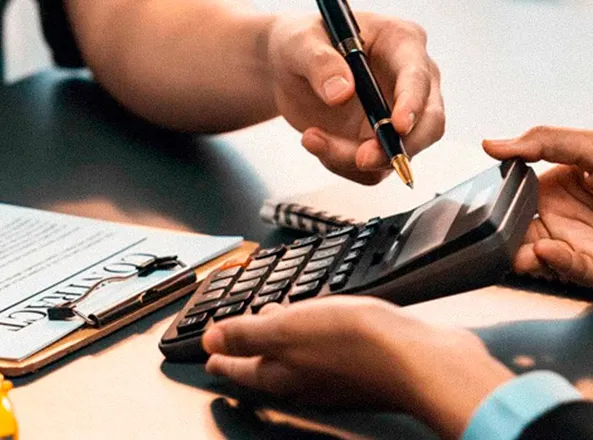 Hands working through figures with a calculator and a pen