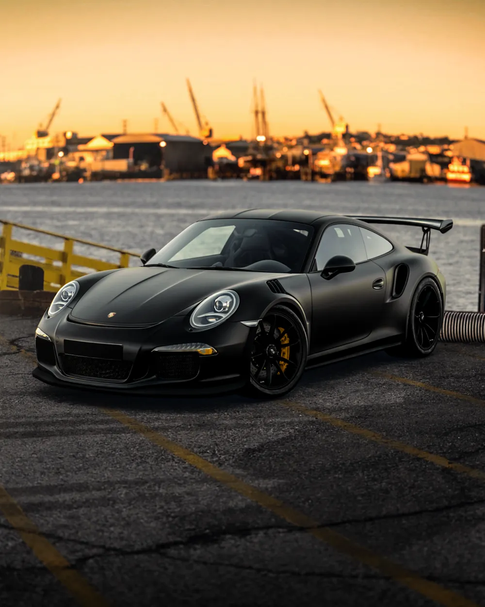 A black sports car parked by the water at sunset